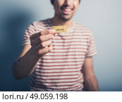 A happy young man is showing a cinema ticket. Стоковое фото, агентство Ingram Publishing / Фотобанк Лори