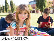 Group of little students sitting on the grass at school. Стоковое фото, агентство Ingram Publishing / Фотобанк Лори