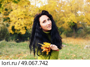 Excited happy fall woman smiling joyful and blissful holding autumn leaves outside in colorful fall forest. Young woman in beautiful autumn park, concept autumn. Стоковое фото, агентство Ingram Publishing / Фотобанк Лори