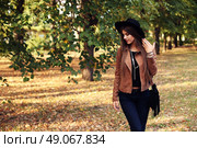 Street fashion concept - closeup portrait of a pretty girl. Wearing hat and suede jacket holding bag with fringe. Beautiful autumn woman. . Стоковое фото, агентство Ingram Publishing / Фотобанк Лори