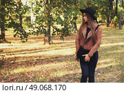 Street fashion concept - closeup portrait of a pretty girl. Wearing hat and suede jacket holding bag with fringe. Beautiful autumn woman. . Стоковое фото, агентство Ingram Publishing / Фотобанк Лори