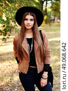 Street fashion concept - closeup portrait of a pretty girl. Wearing hat and suede jacket holding bag with fringe. Beautiful autumn woman. . Стоковое фото, агентство Ingram Publishing / Фотобанк Лори