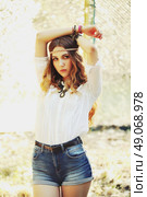 Fashion portrait of beautiful hippie young woman wearing boho chic clothes and summer hat outdoors. Soft warm vintage color tone. Artsy bohemian style. Стоковое фото, агентство Ingram Publishing / Фотобанк Лори