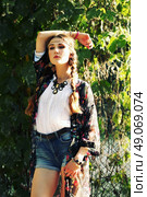 Fashion portrait of beautiful hippie young woman wearing boho chic clothes and summer hat outdoors. Soft warm vintage color tone. Artsy bohemian style. Стоковое фото, агентство Ingram Publishing / Фотобанк Лори