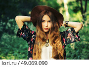 Fashion portrait of beautiful hippie young woman wearing boho chic clothes and summer hat outdoors. Soft warm vintage color tone. Artsy bohemian style. Стоковое фото, агентство Ingram Publishing / Фотобанк Лори