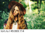 Fashion portrait of beautiful hippie young woman wearing boho chic clothes and summer hat outdoors. Soft warm vintage color tone. Artsy bohemian style. Стоковое фото, агентство Ingram Publishing / Фотобанк Лори