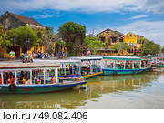 Colorful traditional Vietnamese boats adorned with lanterns lined up by the riverside, celebrating the lantern festival in Hoi An. Vietnam, Hoi An - December 1, 2024. Редакционное фото, фотограф Корчагина Анастасия / Фотобанк Лори