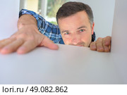 Kitchen fitter installing a cupboard. Стоковое фото, агентство Ingram Publishing / Фотобанк Лори