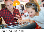 Young lady putting stylus onto record, man urging caution. Стоковое фото, агентство Ingram Publishing / Фотобанк Лори