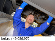 Mechanic in pit checking underneath of vehicle. Стоковое фото, агентство Ingram Publishing / Фотобанк Лори