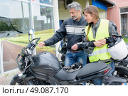 Man explaining controls of a motorcycle to a lady. Стоковое фото, агентство Ingram Publishing / Фотобанк Лори