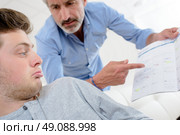 Man pointing angrily at book, young man feigning ignorance. Стоковое фото, агентство Ingram Publishing / Фотобанк Лори
