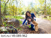 Mother and daughter in a park picking clover plants. Стоковое фото, агентство Ingram Publishing / Фотобанк Лори