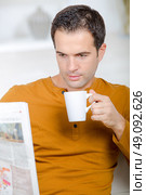 Man drinking coffee whilst reading the newspaper. Стоковое фото, агентство Ingram Publishing / Фотобанк Лори