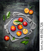 Halves of peaches or nectarines in gray stone plate with leaves, top view. Стоковое фото, агентство Ingram Publishing / Фотобанк Лори