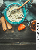 Creme for tiramisu making. Mascarpone cheese with Italian amaretto liqueur in blue bowl on dark rustic wooden background, top view, place for text. Italian food concept. Стоковое фото, агентство Ingram Publishing / Фотобанк Лори