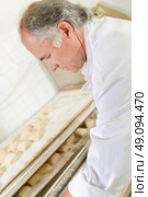 Baker preparing trays of bread rolls. Стоковое фото, агентство Ingram Publishing / Фотобанк Лори