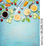 Salad making. Cutlery and dressing ingredients for fresh salad on light blue background, top view place for text. Vinegar ,mustard,oil and honey with chopped vegetables and lettuce leaves. Стоковое фото, агентство Ingram Publishing / Фотобанк Лори