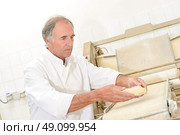 Baker placing dough onto conveyor. Стоковое фото, агентство Ingram Publishing / Фотобанк Лори