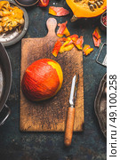 Pumpkin peeling on rustic cutting board with vegetables peeler , dark wooden background, top view. Стоковое фото, агентство Ingram Publishing / Фотобанк Лори