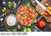 Caprese tomatoes mozzarella salad  on dark rustic background with oil, balsamic vinegar, cutting board and ingredients, top view. Стоковое фото, агентство Ingram Publishing / Фотобанк Лори