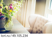 Glass vase with  wild field flowers bunch on dinning table with chair at window. Floral home decoration. Стоковое фото, агентство Ingram Publishing / Фотобанк Лори