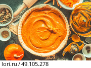 Traditional festive pumpkin pie preparation on rustic kitchen table with cooking tools, top view, retro styled. Стоковое фото, агентство Ingram Publishing / Фотобанк Лори