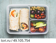 Healthy lunch box with vegetarian tortilla wraps, chopped vegetables and fruits on wooden background , top view. Стоковое фото, агентство Ingram Publishing / Фотобанк Лори
