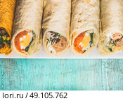 Various of tasty wraps on light wooden background, top view, border. Healthy lunch snack or street food concept. Стоковое фото, агентство Ingram Publishing / Фотобанк Лори