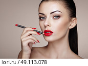 Beautiful woman paints lips with lipstick. Beautiful woman face. Makeup detail. Beauty girl with perfect skin. Стоковое фото, агентство Ingram Publishing / Фотобанк Лори