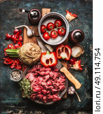 Beef goulash of young bulls with vegetables and cooking ingredients , preparation on cutting  board and dark rustic background , top view composing. Стоковое фото, агентство Ingram Publishing / Фотобанк Лори