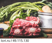Beef Ox tail meat  on kitchen table with cooking pot and vegetables ingredient, side view, close up. Стоковое фото, агентство Ingram Publishing / Фотобанк Лори