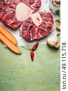 Raw veal shank meat and ingredients for Osso Buco cooking on rustic background, top view, vertical border. Стоковое фото, агентство Ingram Publishing / Фотобанк Лори