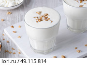 Kefir, buttermilk or yogurt, cottage cheese with granola. Yogurt in glass on white wooden background. Probiotic cold fermented dairy drink. Gut health, fermented products, healthy gut flora concept. Стоковое фото, фотограф Наталия Попова / Фотобанк Лори