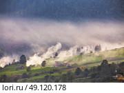 Alpine village in mountains. Smoke, bonfire and haze over the hills in Carpathians. Стоковое фото, агентство Ingram Publishing / Фотобанк Лори