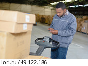 Man by pallet truck, using mobile phone. Стоковое фото, агентство Ingram Publishing / Фотобанк Лори
