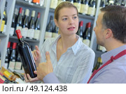 sommelier giving woman recommendation for bottle of wine. Стоковое фото, агентство Ingram Publishing / Фотобанк Лори