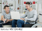 handicapped young man and friend checking music on a laptop. Стоковое фото, агентство Ingram Publishing / Фотобанк Лори