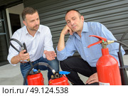 Men looking at fire extinguishers. Стоковое фото, агентство Ingram Publishing / Фотобанк Лори