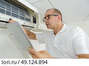 man checking airconditioning manual while using it. Стоковое фото, агентство Ingram Publishing / Фотобанк Лори