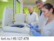 Three lab technicians using machinery. Стоковое фото, агентство Ingram Publishing / Фотобанк Лори
