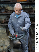 senior blacksmith forging metal on the anvil. Стоковое фото, агентство Ingram Publishing / Фотобанк Лори