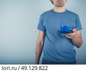 A young man wearing a blue t-shirt is holding a cup of cappucino. Стоковое фото, агентство Ingram Publishing / Фотобанк Лори