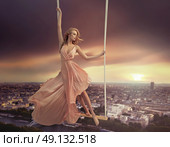 Adorable woman dangling above the city. Стоковое фото, агентство Ingram Publishing / Фотобанк Лори
