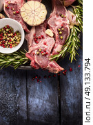Raw lamb meat with peppercorn, rosemary and garlic on blue rustic wooden table, place for text. Стоковое фото, агентство Ingram Publishing / Фотобанк Лори