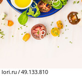Tomatoes salad making with oil and cress on white wooden background, top view. Стоковое фото, агентство Ingram Publishing / Фотобанк Лори