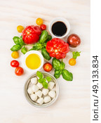 Mozzarella tomatoes salad ingredients with basil leaves,oil and balsamic vinegar, preparation on white wooden background, top view. Стоковое фото, агентство Ingram Publishing / Фотобанк Лори
