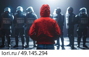 A person wearing a red jacket stands in front of a group of police officers in a confrontational stance. Стоковое AI-изображение, AI-художник Данила Большаков / Фотобанк Лори