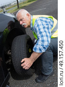 aged man changing leaking tire on the verge. Стоковое фото, агентство Ingram Publishing / Фотобанк Лори