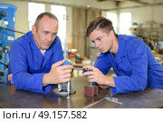 Instructor and trainee examining metal items. Стоковое фото, агентство Ingram Publishing / Фотобанк Лори